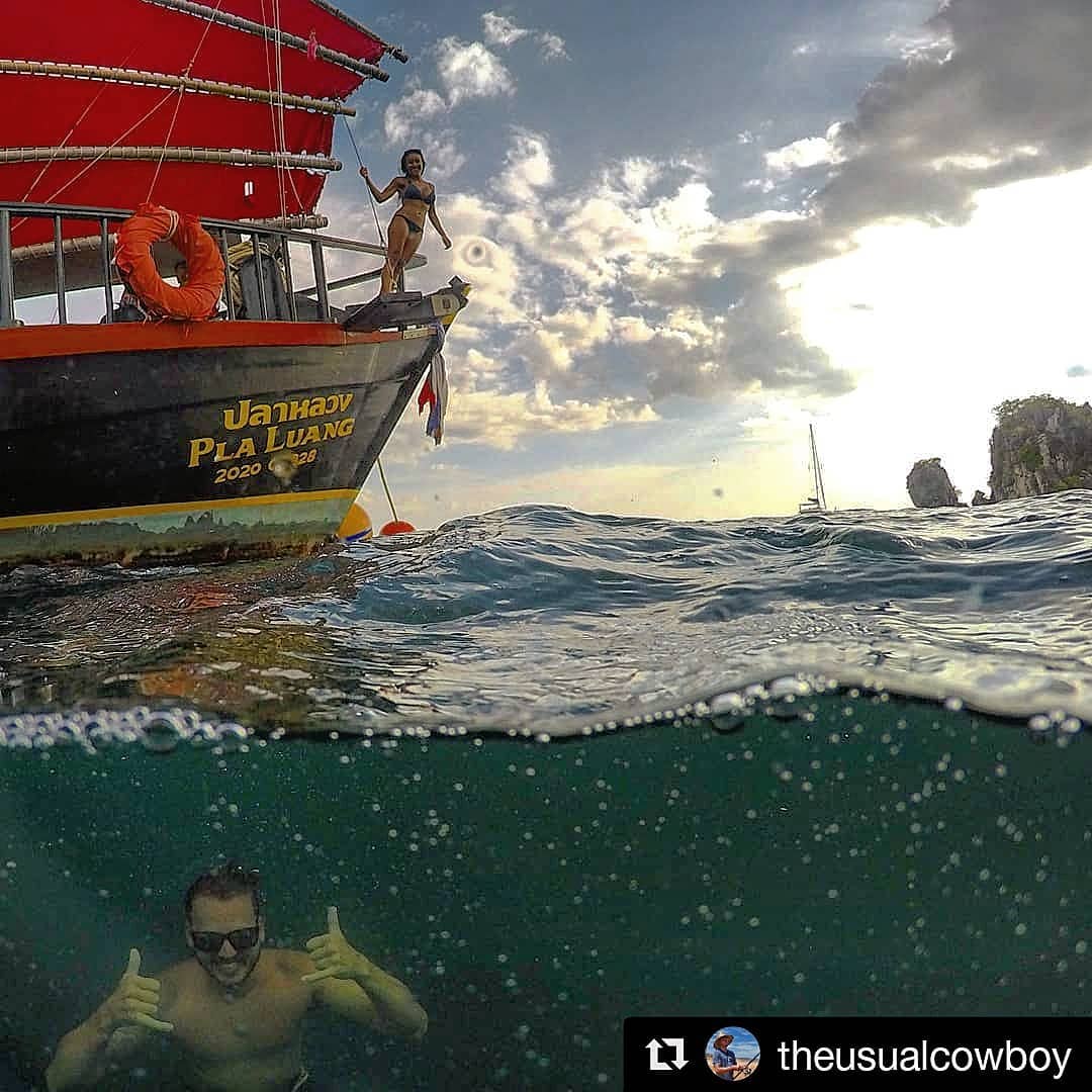 regram instagram photo par le cowboy habituel d'un homme sous l'eau souriant à l'appareil photo et d'une femme hors de l'eau sur un bateau avec une voile rouge