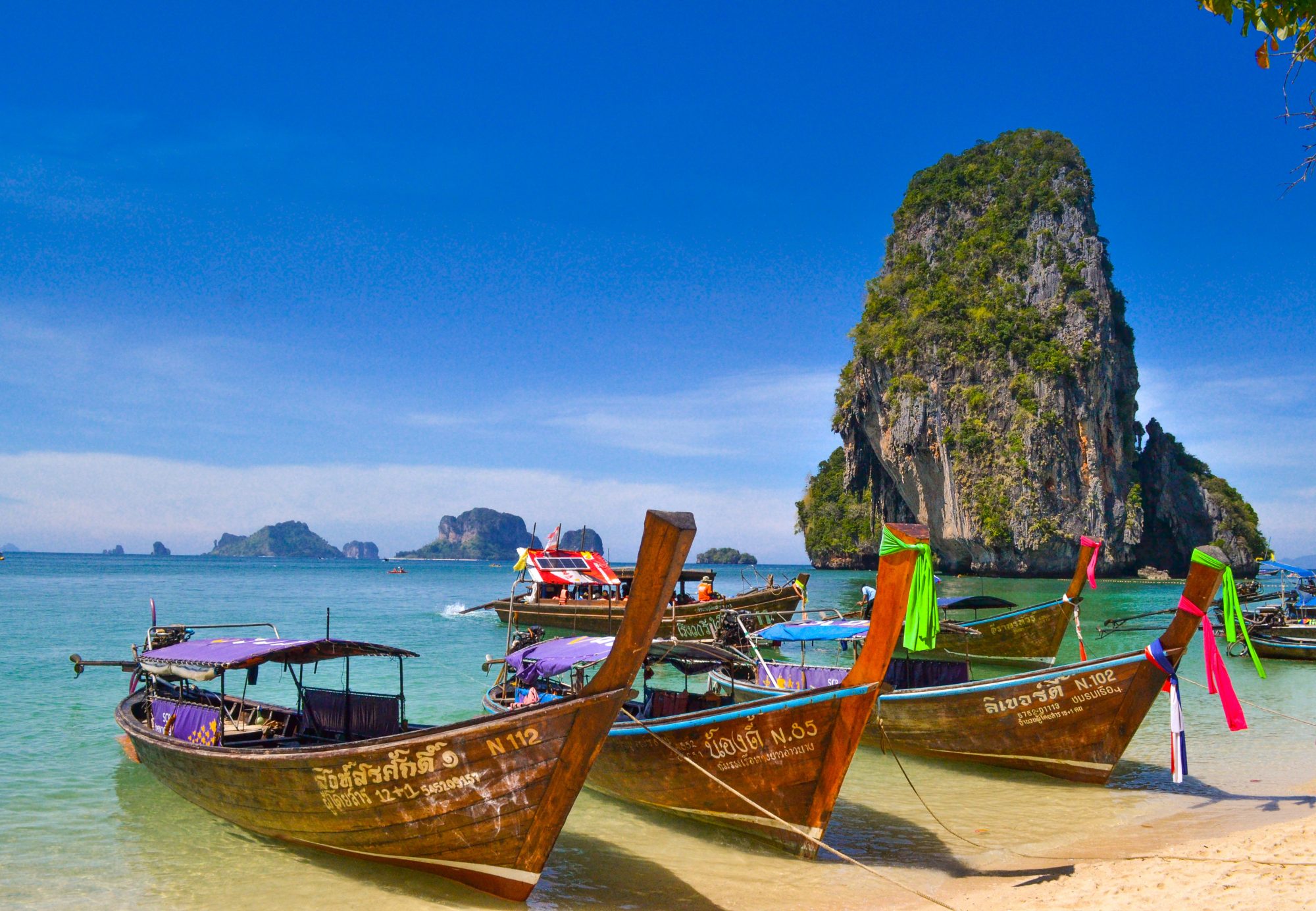 coloridas barcas de cola larga en la playa de railay con las islas al fondo