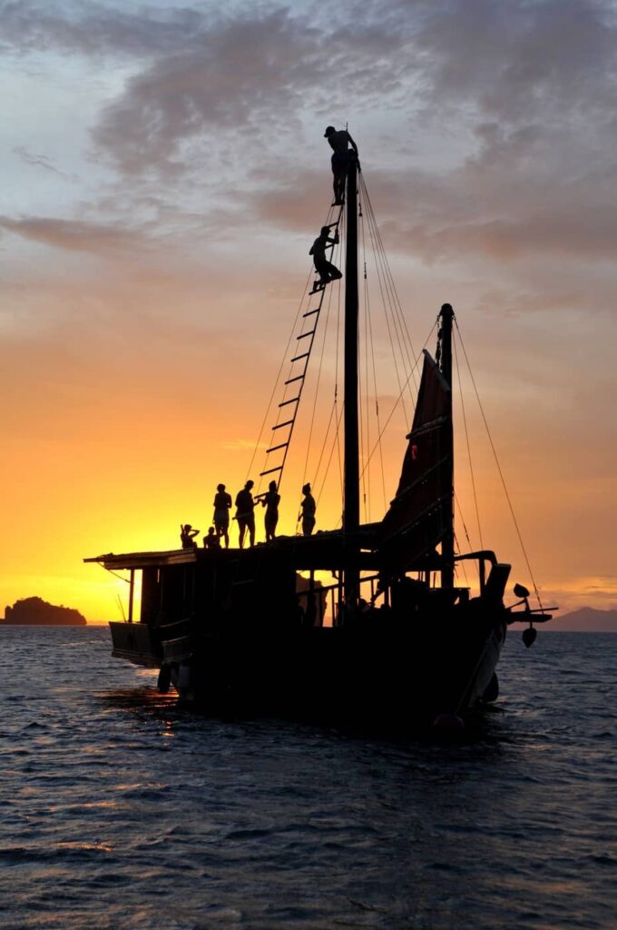 Silhouette of the Krabi Sunset Cruises traditional wooden junk boat against a colourful sunset in Krabi