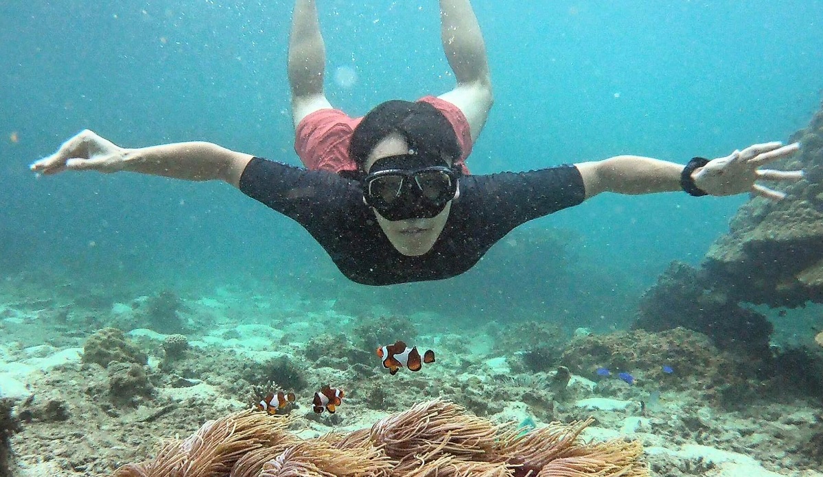 un homme nageant sous l'eau avec un masque de plongée face à la caméra avec un poisson clown devant lui lors d'une excursion en bateau à Krabi