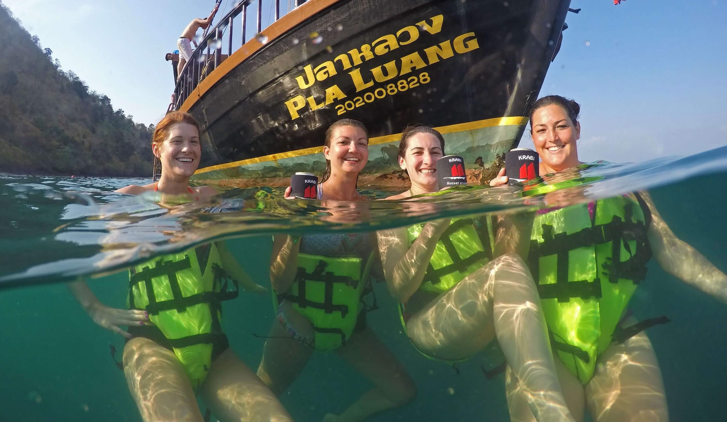 4 personnes dans l'eau avec le bateau krabi sunset cruises en arrière-plan