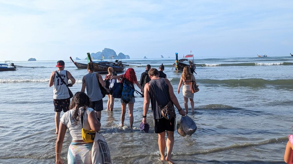 groupe de personnes pataugeant dans l'eau pour rejoindre un bateau à longue queue à krabi