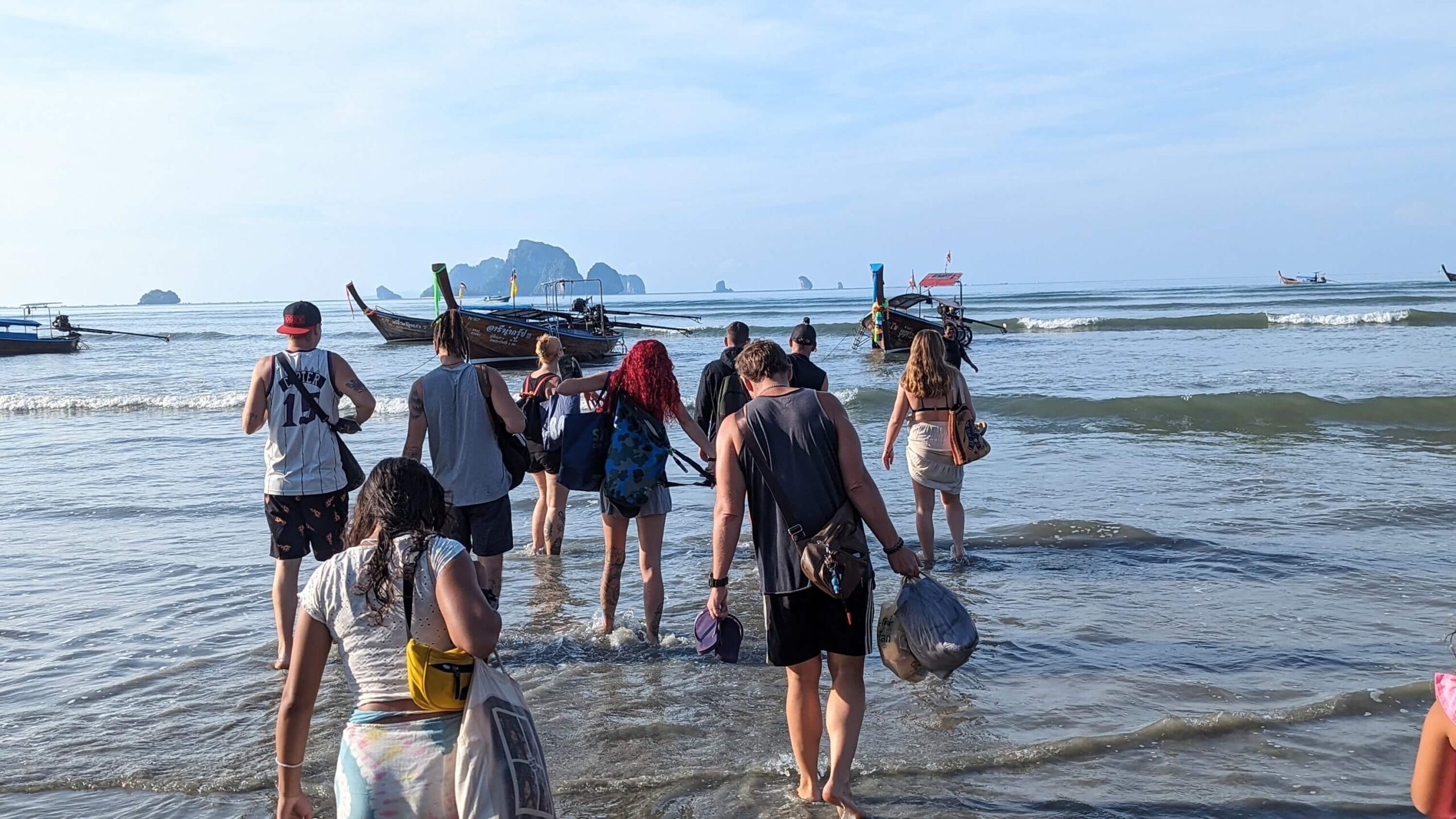 groupe de personnes pataugeant dans l'eau pour rejoindre un bateau à longue queue à krabi