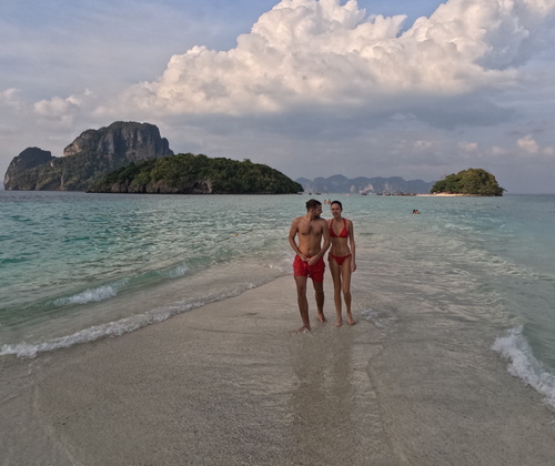Couple standing on a sandbar surrounded by turquoise waters with koh Tup and Poda Island in the background