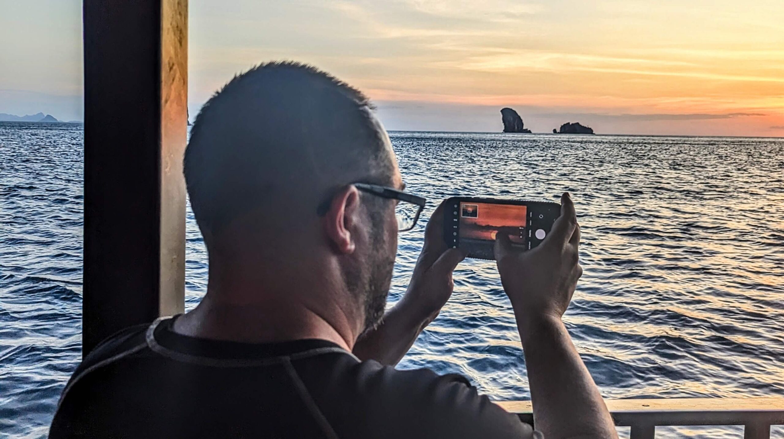 homme prenant une photo d'un coucher de soleil avec son téléphone