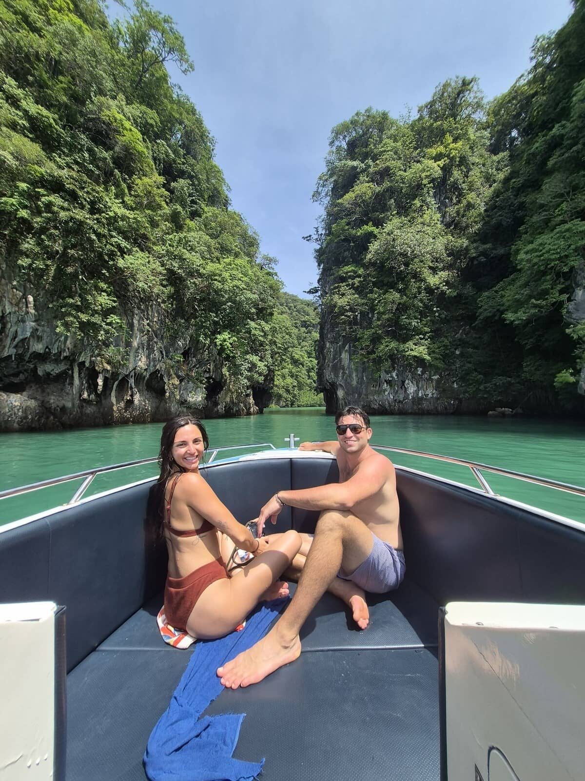 Un couple assis à l'avant d'un hors-bord à Krabi, avec des falaises calcaires en arrière-plan.