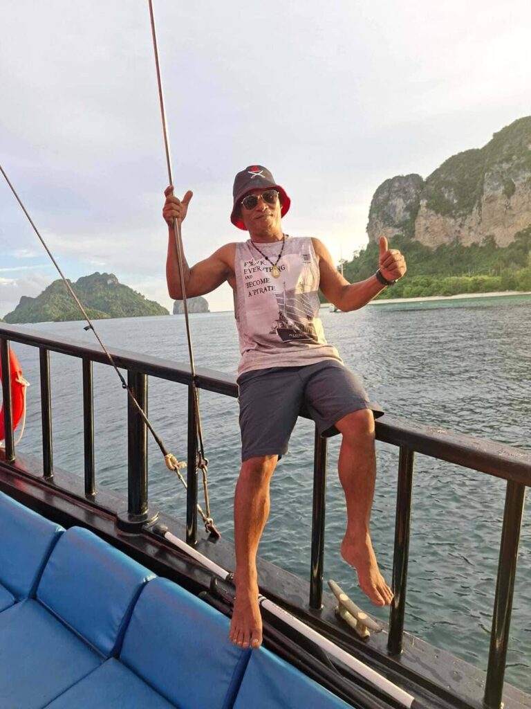 Pi Mee, captain of Krabi Sunset Cruises, standing aboard the traditional wooden boat